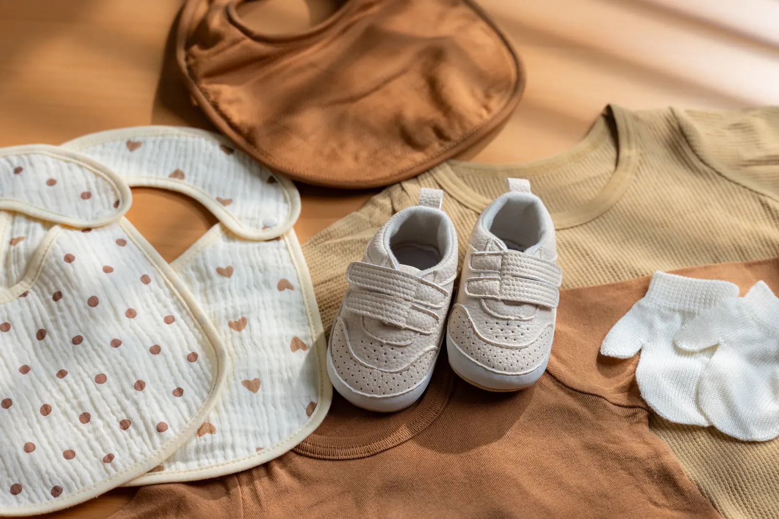 Babadores de musselina com corações, blusas de algodão waffle bege e marrom, tênis bege e luvinhas brancas